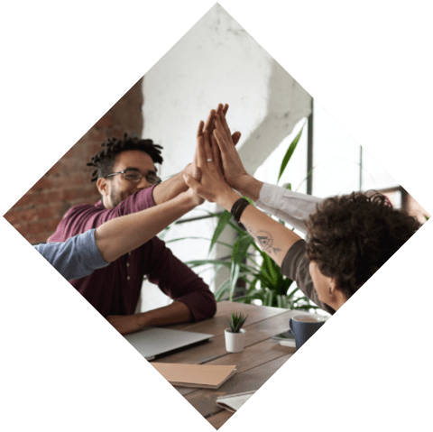 A group of people sitting at a table with their hands in the air.